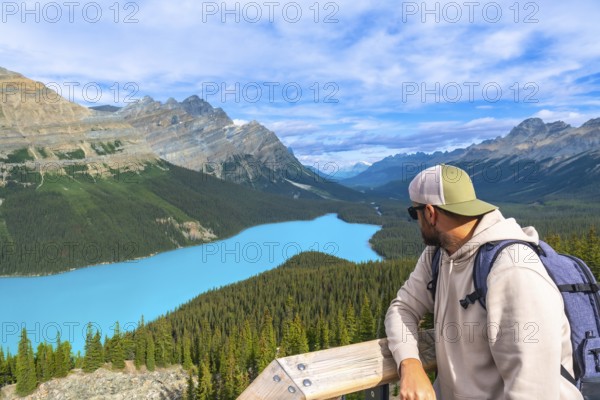 Hiker enjoying breathtaking view of turquoise peyto lake and surrounding canadian rockies mountains in banff national park, alberta, a popular tourist destination