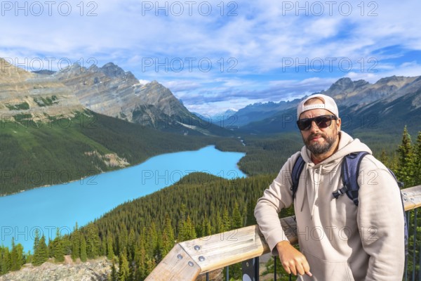 Backpacker standing on a scenic viewpoint, enjoying the stunning turquoise waters of peyto lake and the surrounding canadian rockies in banff national park, alberta, on a beautiful sunny day