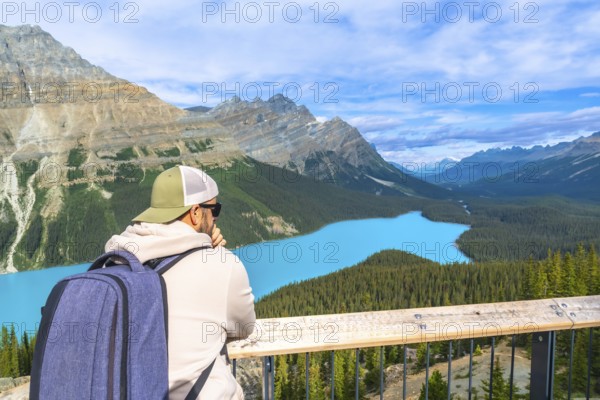 Tourist with backpack is enjoying the breathtaking panoramic view of the turquoise peyto lake and surrounding canadian rockies in banff national park, alberta, on a beautiful sunny day