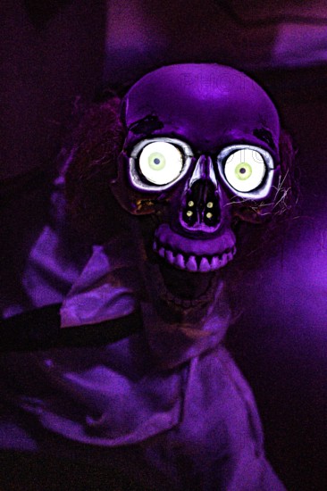 A scary skeleton with glowing eyes in purple lighting in an escape room, Lower Saxony, Germany