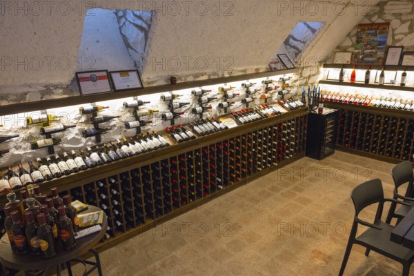 Wine cellar with illuminated shelves full of wine bottles and simple chairs and tables for tastings, Georgian-German wine house from 1915, Bolnissi, Katharinenfeld, founded by Caucasian German settlers, Lower Kartli region, Kwemo Kartli, Georgia