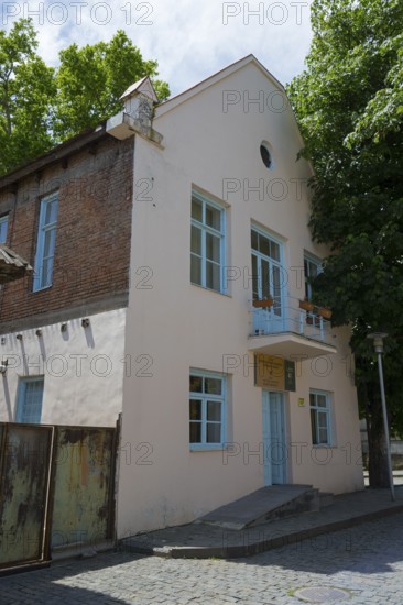 Two-storey building with bricks and blue door, surrounded by trees on a sunny day, Katharinenfeld administration building, restoration 2019-2021, Bolnissi, Katharinenfeld, founded by Caucasian German settlers, Lower Kartli region, Kwemo Kartli, Georgia