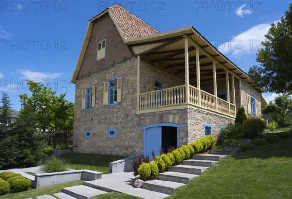 Traditional stone house with veranda and shutters, surrounded by well-kept garden under blue sky, Georgian-German wine house from 1915, Bolnissi, Katharinenfeld, founded by Caucasian German settlers, Lower Kartli region, Kwemo Kartli, Georgia