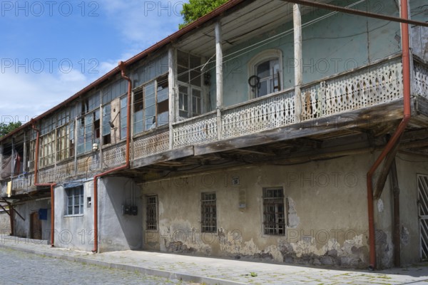 Elongated balcony of an old building with weathered wooden railings under a clear blue sky, traditional German residential building, Nikolaistraße 30, Bolnissi, Katharinenfeld, founded by Caucasian German settlers, Lower Kartli region, Kwemo Kartli, Georgia