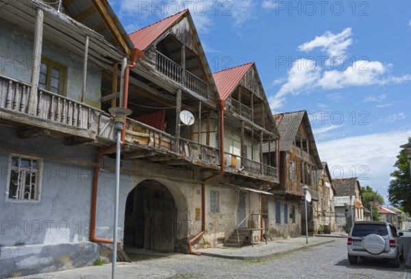 Street view with old wooden houses and balconies under blue sky with parked cars, traditional German residential building, Nikolaistraße 46, Bolnissi, Katharinenfeld, founded by Caucasian German settlers, Lower Kartli region, Kwemo Kartli, Georgia