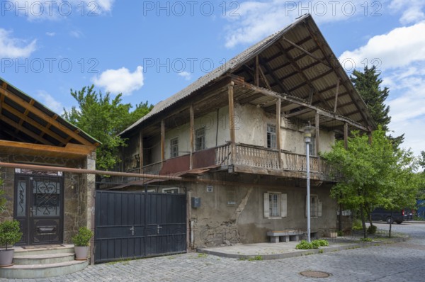 Old, two-story building with wooden roof and balconies surrounded by trees, traditional German residential building, Nikolaistraße 50, corner of Kirchstraße, Bolnissi, Katharinenfeld, founded by Caucasian German settlers, Lower Kartli region, Kwemo Kartli, Georgia