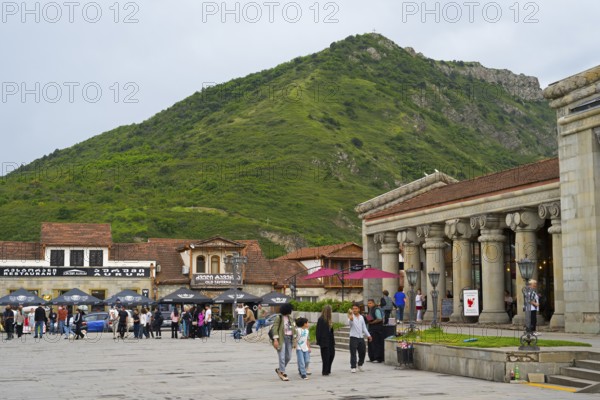 People gather in a square in front of historic buildings and a green mountain backdrop, Mtskheta Square, Mtskheta, Mtskheta, Mtskheta-Mtianeti region, Georgia