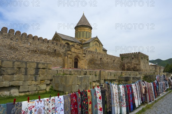 Stone fortress with monastery in the background, lots of colorful fabrics hung in front of it, Svetitskhoveli Cathedral, Svetitskhoveli, UNESCO World Heritage, Mtskheta, Mtskheta, Mtskheta, Mtskheta-Mtianeti region, Georgia