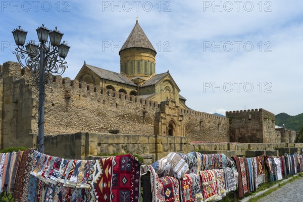 Rugs in front of a historic wall and a church under a blue sky, Svetitskhoveli Cathedral, Svetitskhoveli, UNESCO World Heritage Site, Mtskheta, Mtskheta, Mtskheta-Mtianeti Region, Georgia