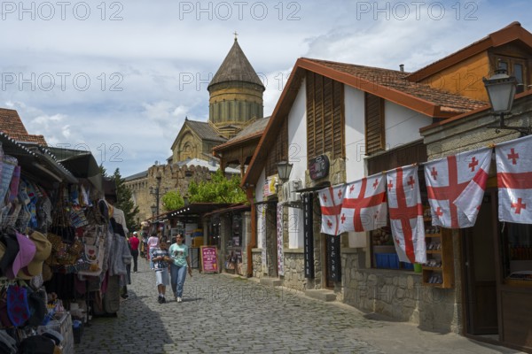 Street with souvenir stands, Georgian flags and a church in the background, Svetitskhoveli Cathedral, Svetitskhoveli, UNESCO World Heritage Site, Mtskheta, Mtskheta, Mtskheta, Mtskheta-Mtianeti region, Georgia