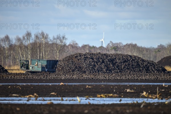 Layered peat sod Peeling of a high-moor black peat in cloudy skies with earthy colors and natural texture. On the left, a special vehicle for torfcutting peat mining, Diepholzer Moorniederung, Drebber, Lower Saxony, Germany