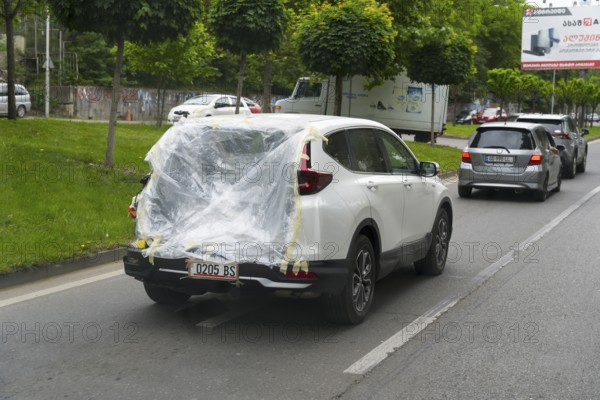 A car drives on the road with plastic wrap over the rear, Tbilisi, Mtskheta-Mtianeti region, Georgia