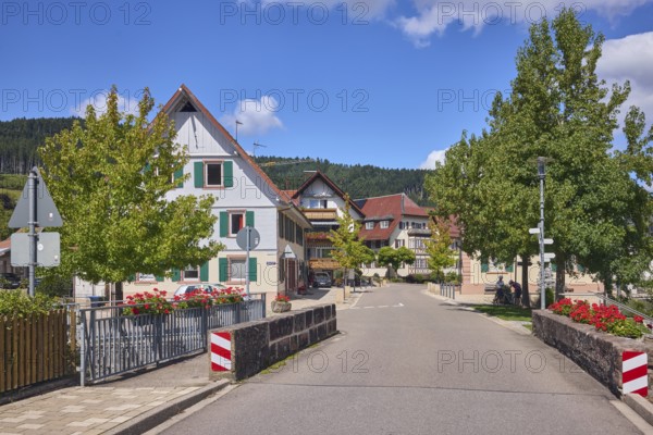 Car bridge and footbridge, sandstone, metal railings, flower boxes, general architecture, buildings, houses, lantern, trees, meadow, hill, coniferous forest, blue sky, cumulus clouds, intersection of main street with Unterdorf, Hofstetten, Black Forest, Ortenaukreis, Baden-Württemberg, Germany
