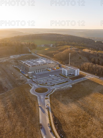 Industrial complex with circular road next to hilly landscape at sunset, future PV construction on old deposit, Lindenrain industrial park, Calw, Germany