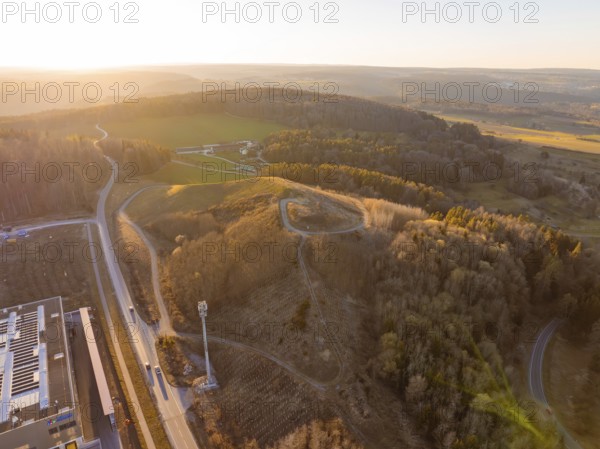 Aerial view of hilly landscape and forest in evening light, future PV building on old deposit, Lindenrain industrial park, Calw, Germany