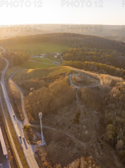 Hilly landscape with roads and dense forest in the light of sunset, future PV building on old deposit, Lindenrain industrial park, Calw, Germany