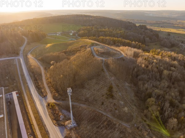 Hilly landscape with forest and roads in the warm light of sunset, future PV building on old deposit, Lindenrain industrial park, Calw, Germany