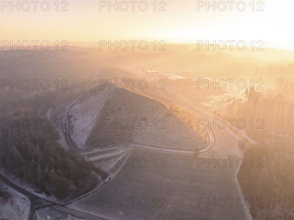 Hill in foggy landscape at sunrise, with surrounding roads and quiet atmosphere, future PV construction on old deposit, Lindenrain industrial park, Calw, Germany