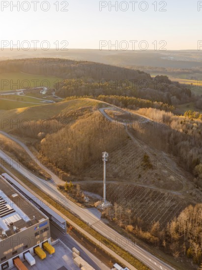 Hilly landscape with forest and telecommunications tower at sunset, future PV building on old deposit, Lindenrain industrial park, Calw, Germany