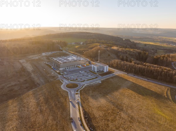 View of industrial plant and hilly landscape in evening light, future PV building on old deposit, Lindenrain industrial park, Calw, Germany
