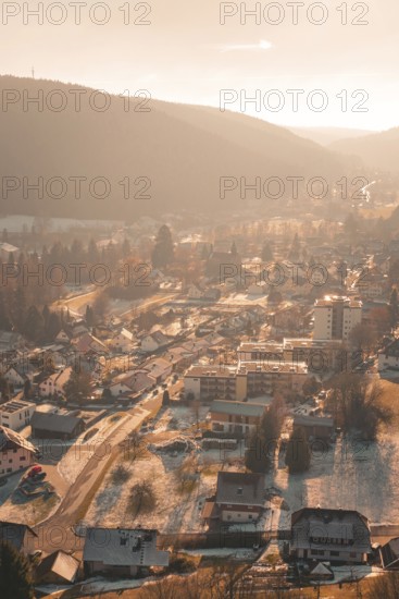 Aerial view of a snowy village in a hilly landscape illuminated by the warm winter sun, Enzklösterle, Calw district, Germany