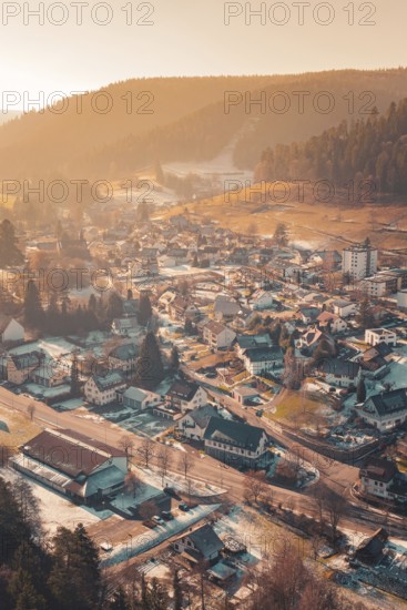View of a snowy village in a wide valley at sunset, surrounded by wooded hills, Enzklösterle, Calw district, Germany