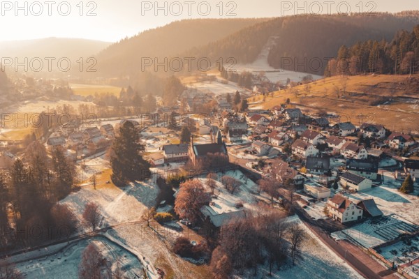Aerial view of a small village in winter nestled in a hilly landscape at sunset, Enzklösterle, Calw district, Germany