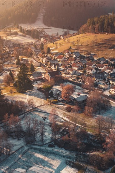 Panoramic view of a snowy village with meadows and a central church in picturesque surroundings, Enzklösterle, Calw district, Germany
