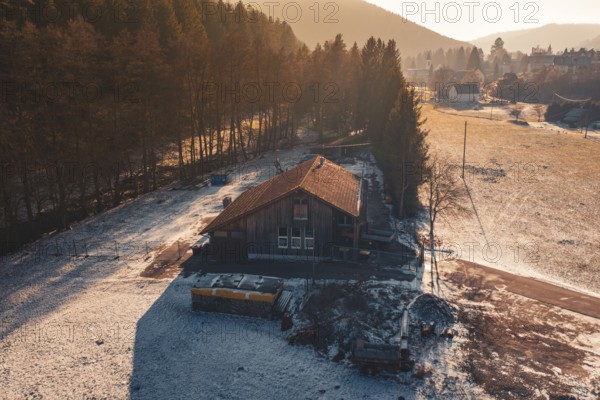 Wooden house on the edge of the forest, surrounded by snow, captured in the warm light of sunset light, Enzklösterle, Calw district, Germany