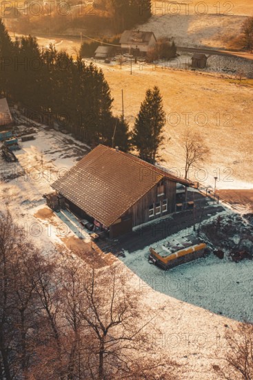 Snowy wooden house in a rural area, illuminated by the warm light tones of sunset, Enzklösterle, Calw district, Germany