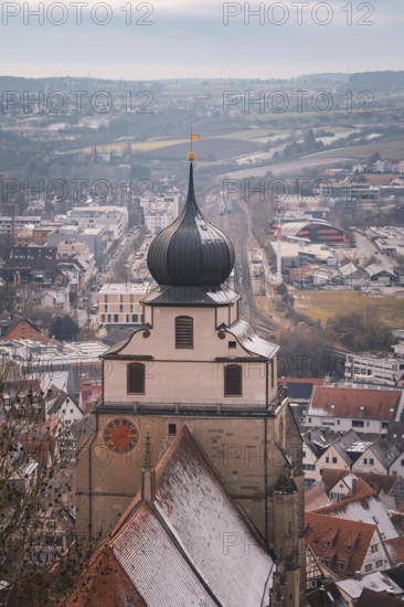 View of a church tower in front of a snow-covered city panorama with vast fields, Herrenberg, Böblingen district, Germany