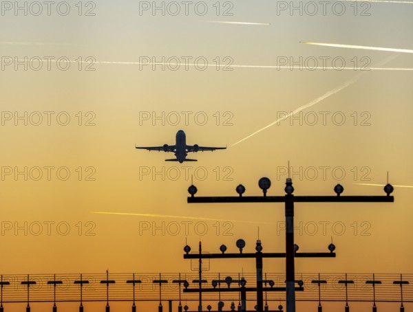 Runway lighting, approach aids, at Düsseldorf International Airport, sunset, aircraft taking off, Hauptbahn Süd, 05R/23L, contrails from aircraft at higher altitudes, North Rhine-Westphalia, Germany