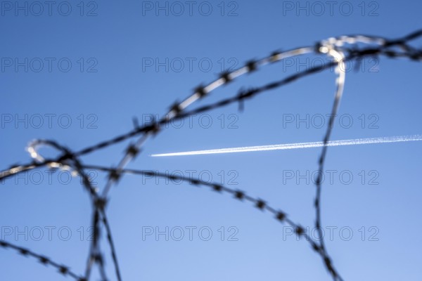 Symbolic picture security at the airport, outer fence at Düsseldorf International Airport, steel wire fence, with S-wire rollers, NATO wire, on the fence crown, airplane with wire strips at high altitude, North Rhine-Westphalia, Germany