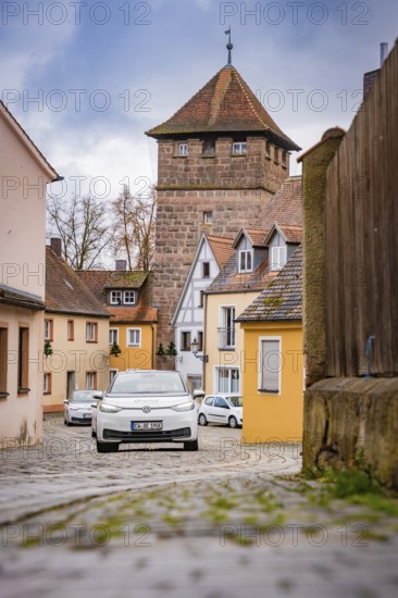 Narrow alley with cobblestones and old defensive towers in a village, ID3, deer e-car sharing, Germany