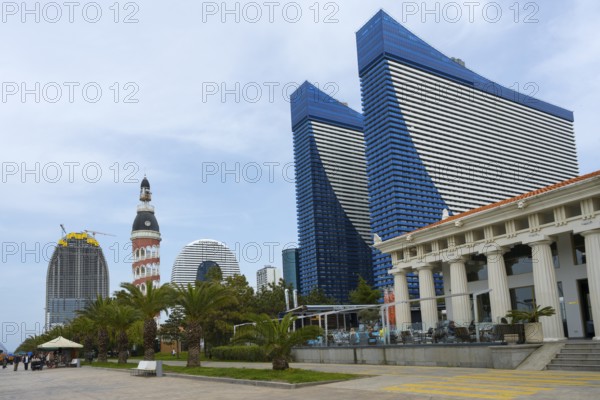 Skyscrapers with blue glass facades next to palm trees and column-supported buildings shape the city scene, Orbi City hotel complex and restaurant Veranda Acropolis, Batumi, Black Sea, Ajara region, Adjara, autonomous republic, Georgia