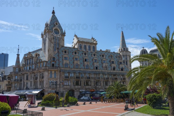 Historic building with towers and palm trees on an open square under a blue sky, Europe Square, Batumi, Black Sea, Ajara region, Adjara, Autonomous Republic, Georgia