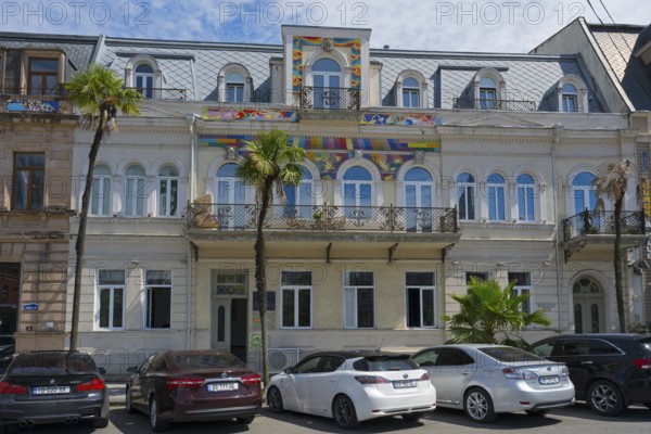 Historic building with palm trees and cars in front of it, colorful decoration over the windows, Europe Square, Batumi, Black Sea, Ajara region, Adjara, Autonomous Republic, Georgia