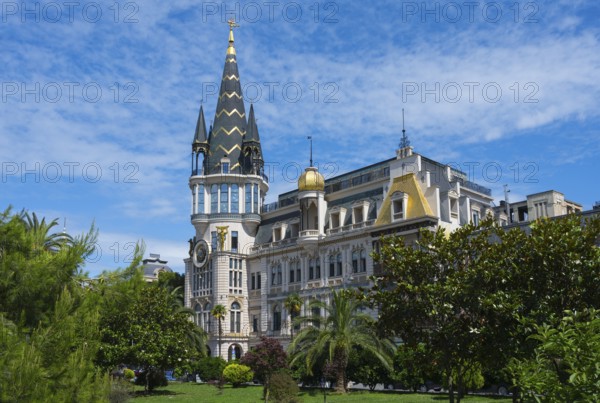 Castle-like building with tall tower and green garden under blue sky, Astronomical Clock, Black Gold Roof, Europe Square, Batumi, Black Sea, Adjara Region, Adjara, Autonomous Republic, Georgia