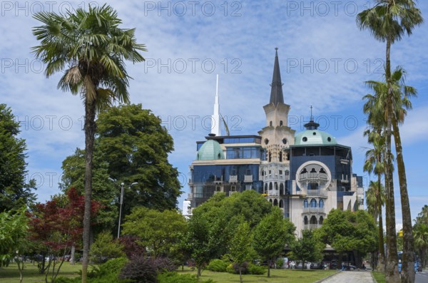 Historic building with tower in the park surrounded by palm trees under a blue sky, former registry office, now administrative building of the government of Adjara, Batumi, Black Sea, Ajara region, Adjara, autonomous republic, Georgia
