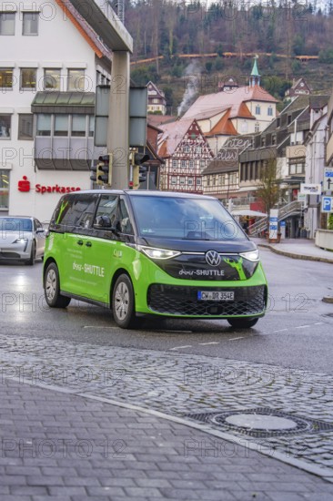 Green car in the city center with half-timbered houses in the background in rainy weather, Deer E-Mobility Shuttle Service, Calw, Germany