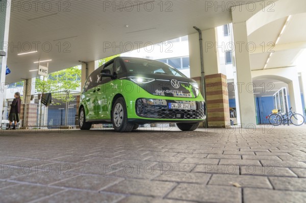 Green VW under roof in urban environment, Deer E-Mobility Shuttle Service, Calw, Germany