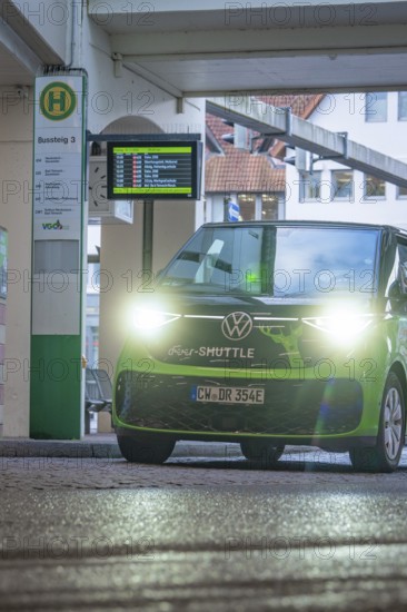 Green VW with lights on at a bus stop at night, Deer E-Mobility Shuttle Service, Calw, Germany