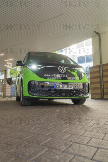 Green VW from the front in an urban, modern environment, Deer E-Mobility Shuttle Service, Calw, Germany