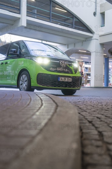 Green Volkswagen shuttle in front of a modern building in an urban area, Deer E-Mobility Shuttle Service, Calw, Germany