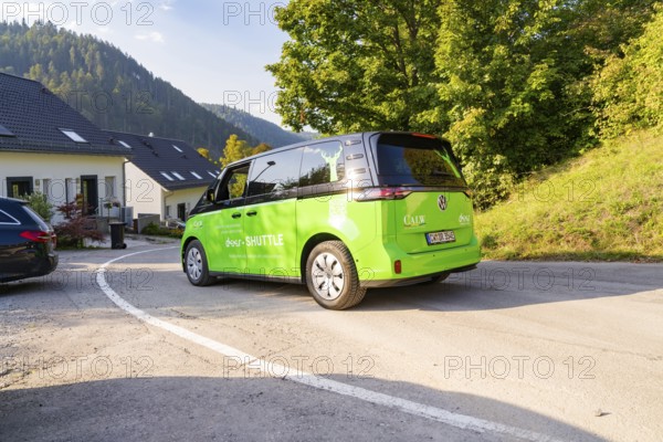 Green car on road in residential area with surrounding natural backdrop, Deer E-Mobility Shuttle Service, Calw, Germany