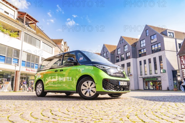 Green car in an urban square with blue sky in the background, Deer E-Mobility Shuttle Service, Calw, Germany