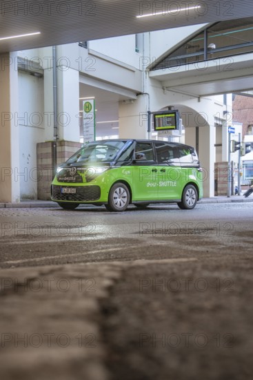 Green shuttle goes around a bend in an urban area, busy atmosphere, Deer E-Mobility Shuttle Service, Calw, Germany