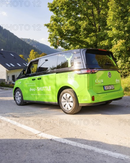 Green car on road in picturesque landscape with mountains in the background, Deer E-Mobility Shuttle Service, Calw, Germany