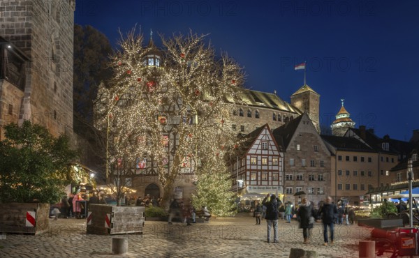 Christmassy illuminated square with the historic Pilate House with advent calendar, in the evening lighting, the Kaiserburg and Sinwell Tower in the back, Beim Tiergärtnertor, Nuremberg, Middle Franconia, Bavaria, Germany