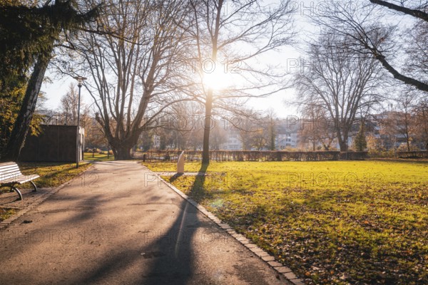 Sunrise illuminates a park path surrounded by autumn trees, Stadtgarten Pforzheim, Germany